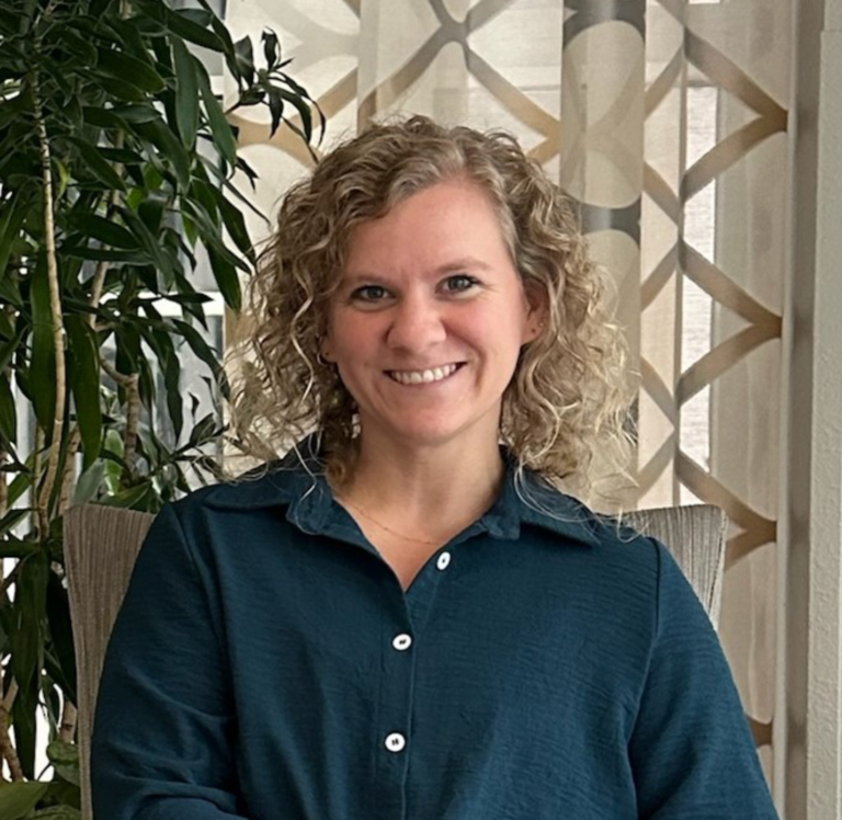 a woman with curly hair sitting on a chair in front of a plant