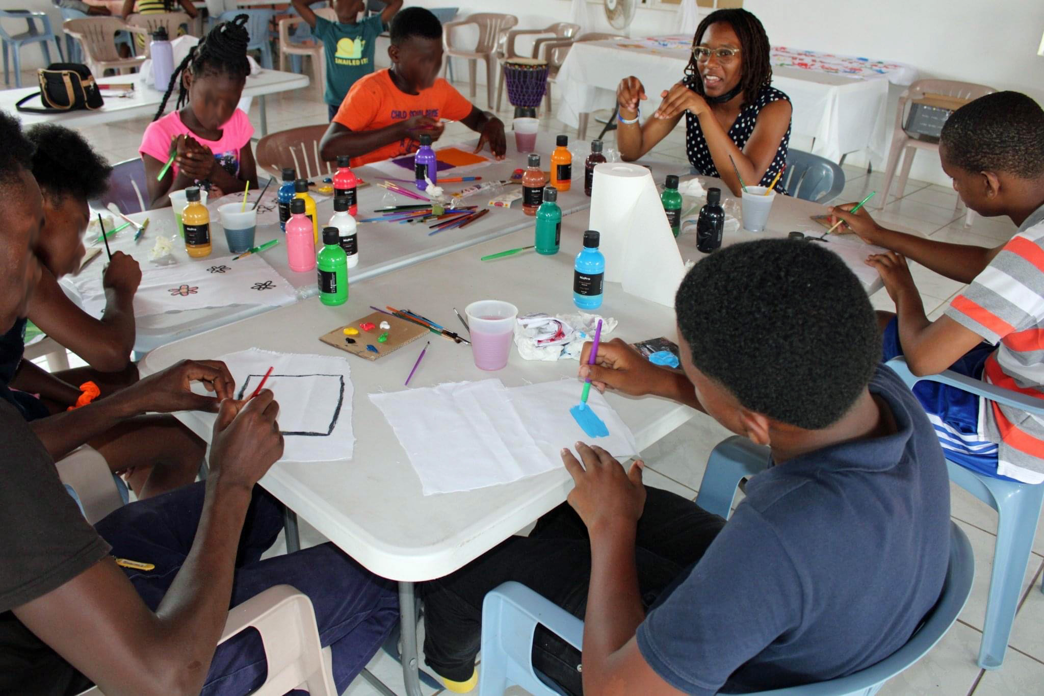a group of children sitting at a table with craft supplies