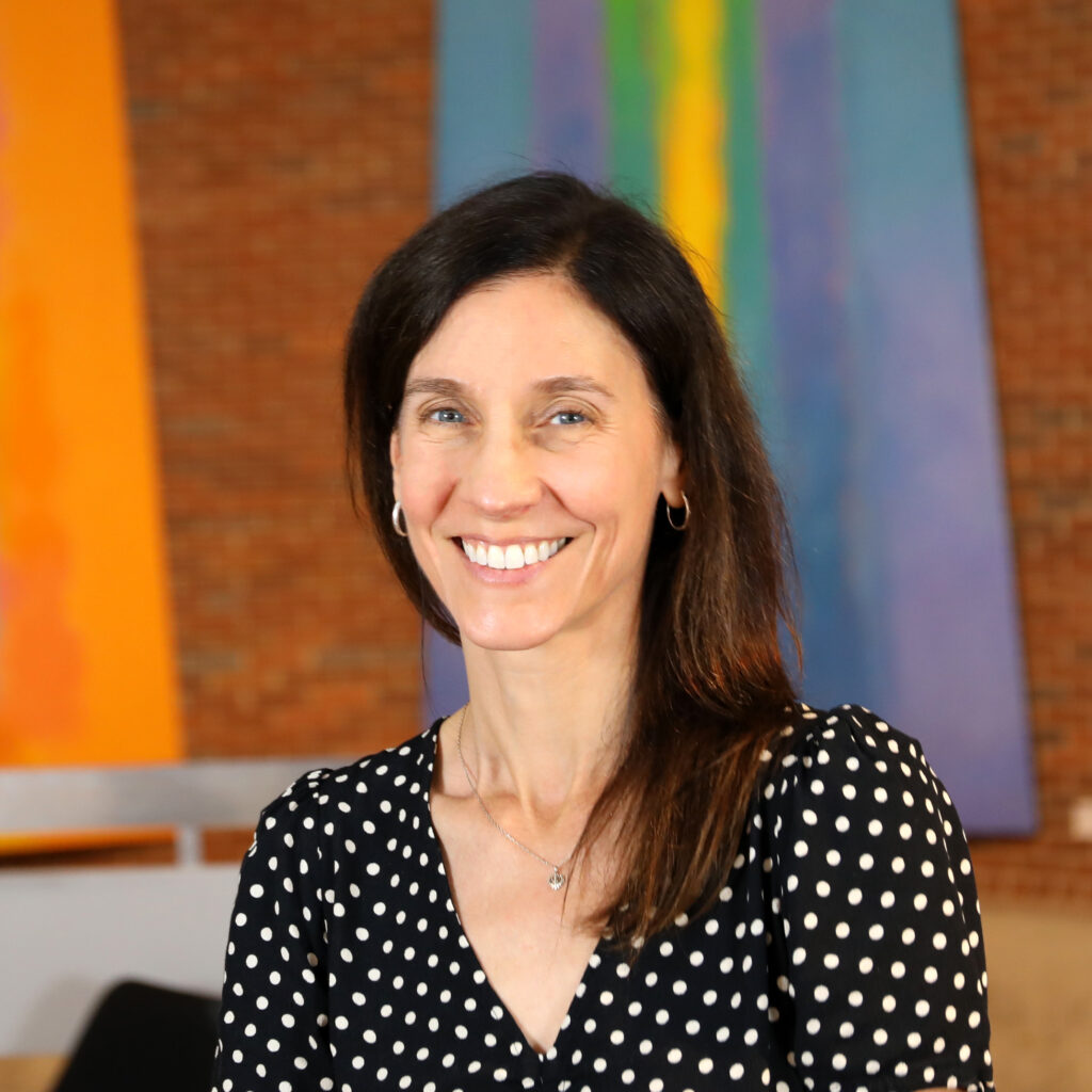 A smiling woman in a black and white polka dot dress