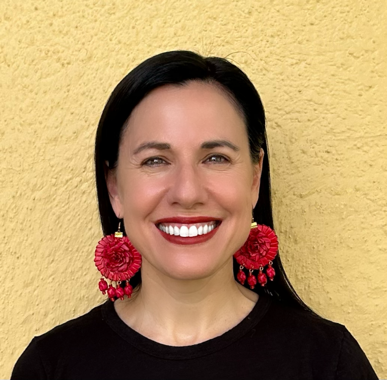 there is a woman that is smiling and wearing some red earrings