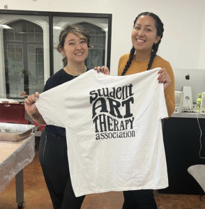 two women holding up a t - shirt with the words sweet art library on it
