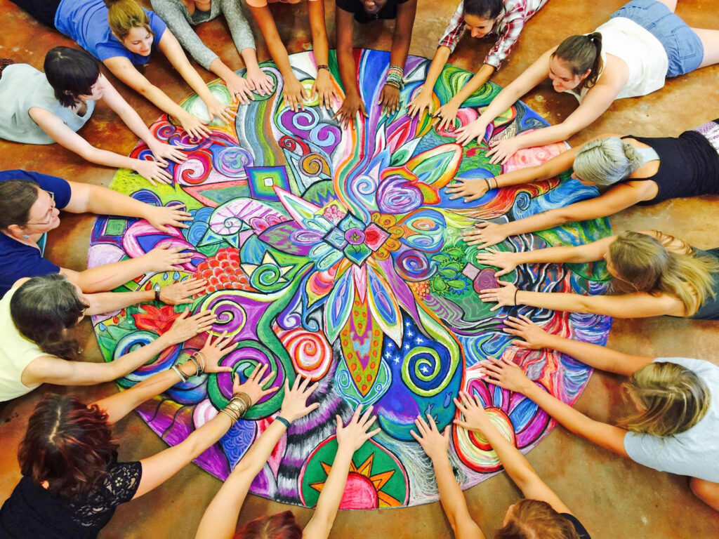 a group of people holding hands around a colorful circle
