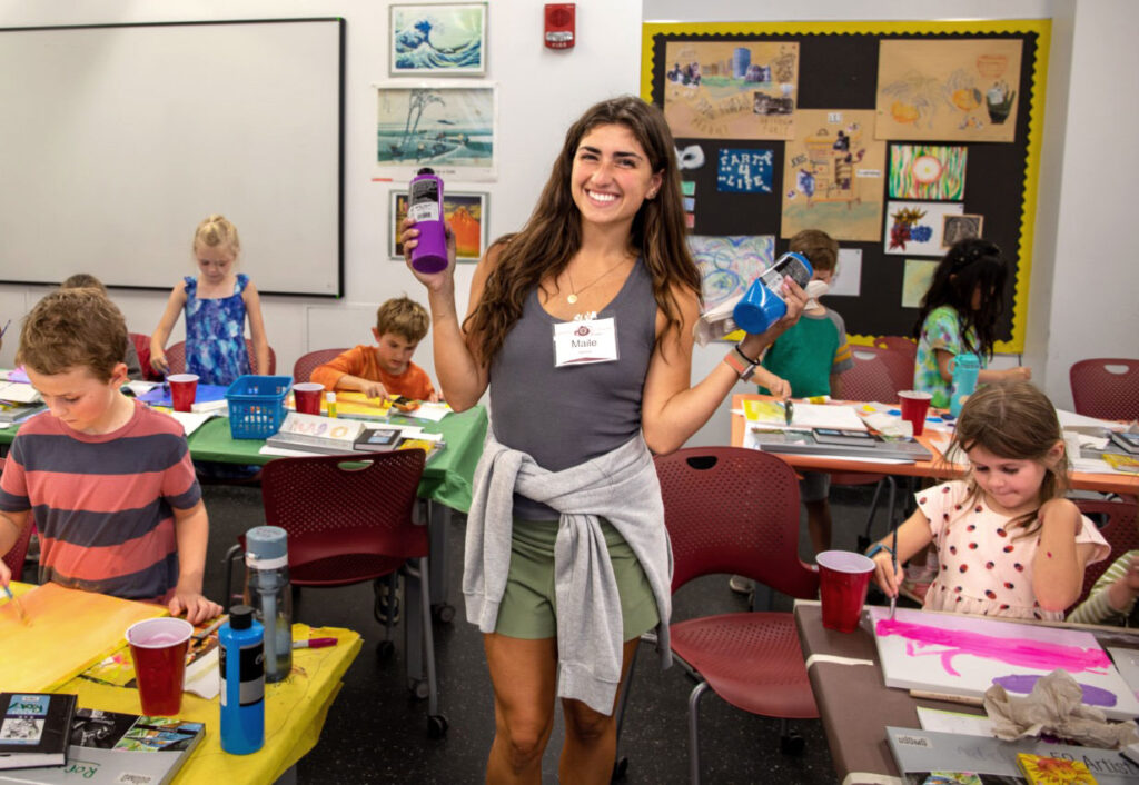 there is a woman standing in front of a classroom full of children