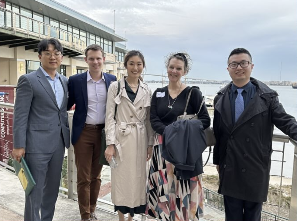 there are four people standing next to each other by the water