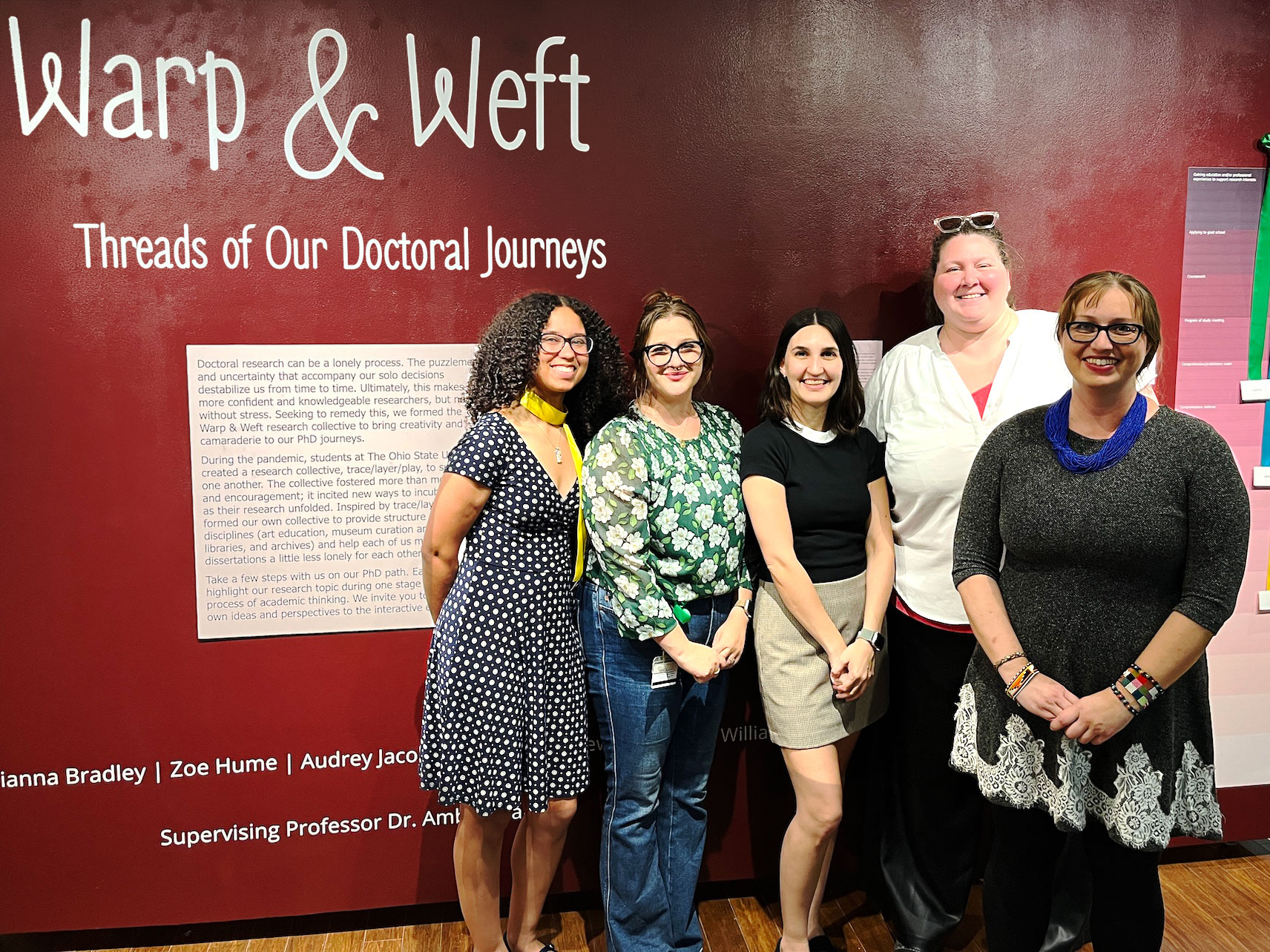 Doctoral students in the Art Education and Museum Education programs stand in front of an exhibition display they co-curated.